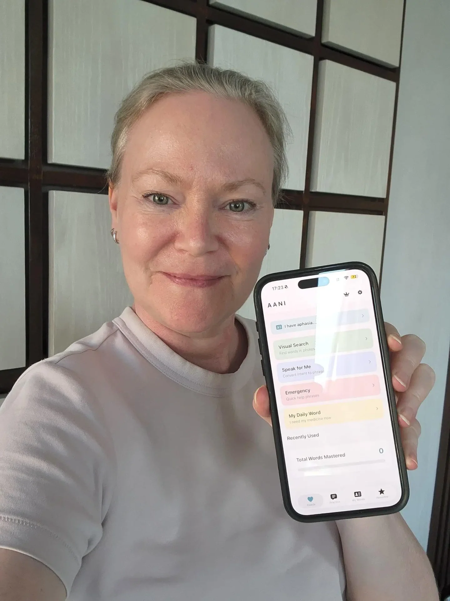 Nina Kolari holding an iPhone showing her Aani app